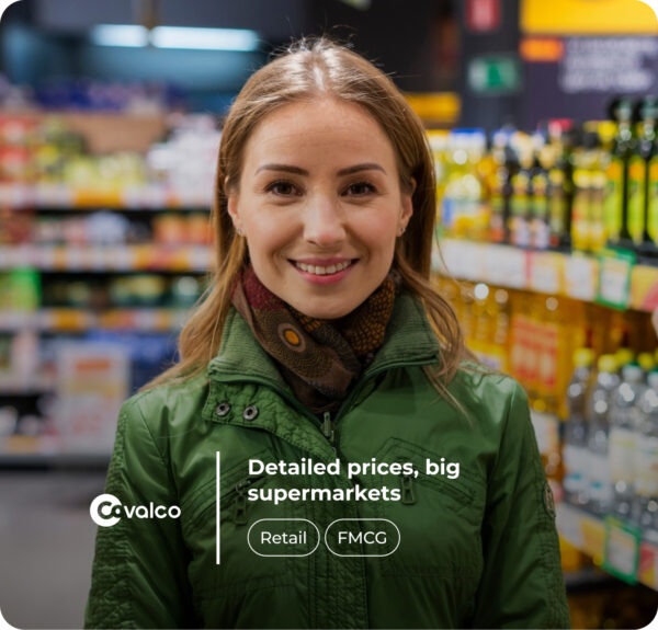 A smiling woman in a green jacket and patterned scarf standing in a supermarket aisle. Shelves stocked with various products, such as bottles and boxes, are blurred in the background. The text overlay includes 'Covalco' with a logo, 'Precios al detalle, supermercados a lo grande,' and buttons labeled 'Retail' and 'FMCG.'"
