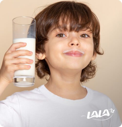 A young boy with a milk mustache holding a tall glass of milk, featuring the LALA brand logo.
