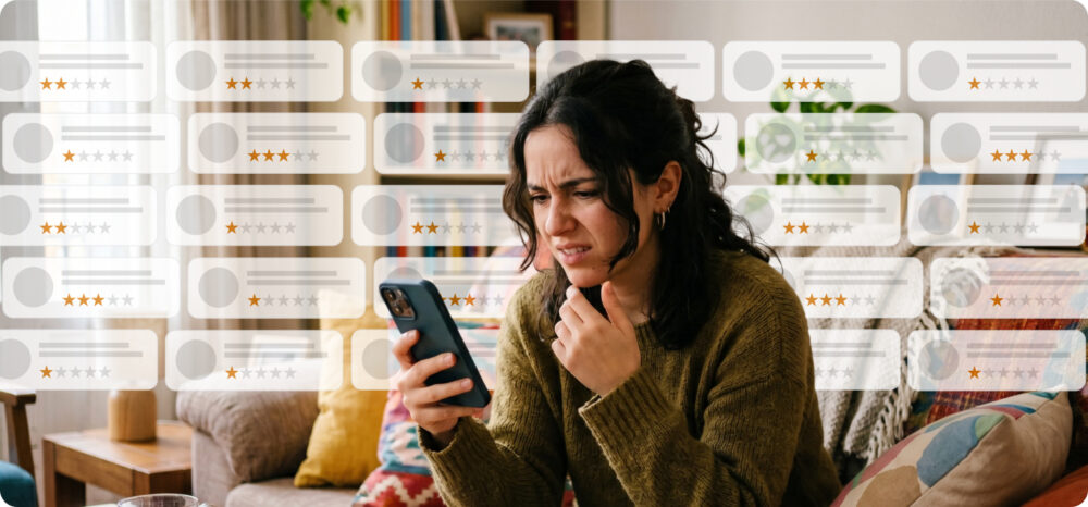 Mulher revisando opiniões negativas em seu celular, cercada de avaliações com poucas estrelas que podem penalizar a percepção da marca.